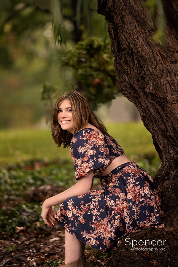 girl in flowered dress smiling for senior pictures at Wade Oval